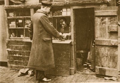 A chauffeur handing in a pair of boots to a cobbler, Mayfair by English Photographer
